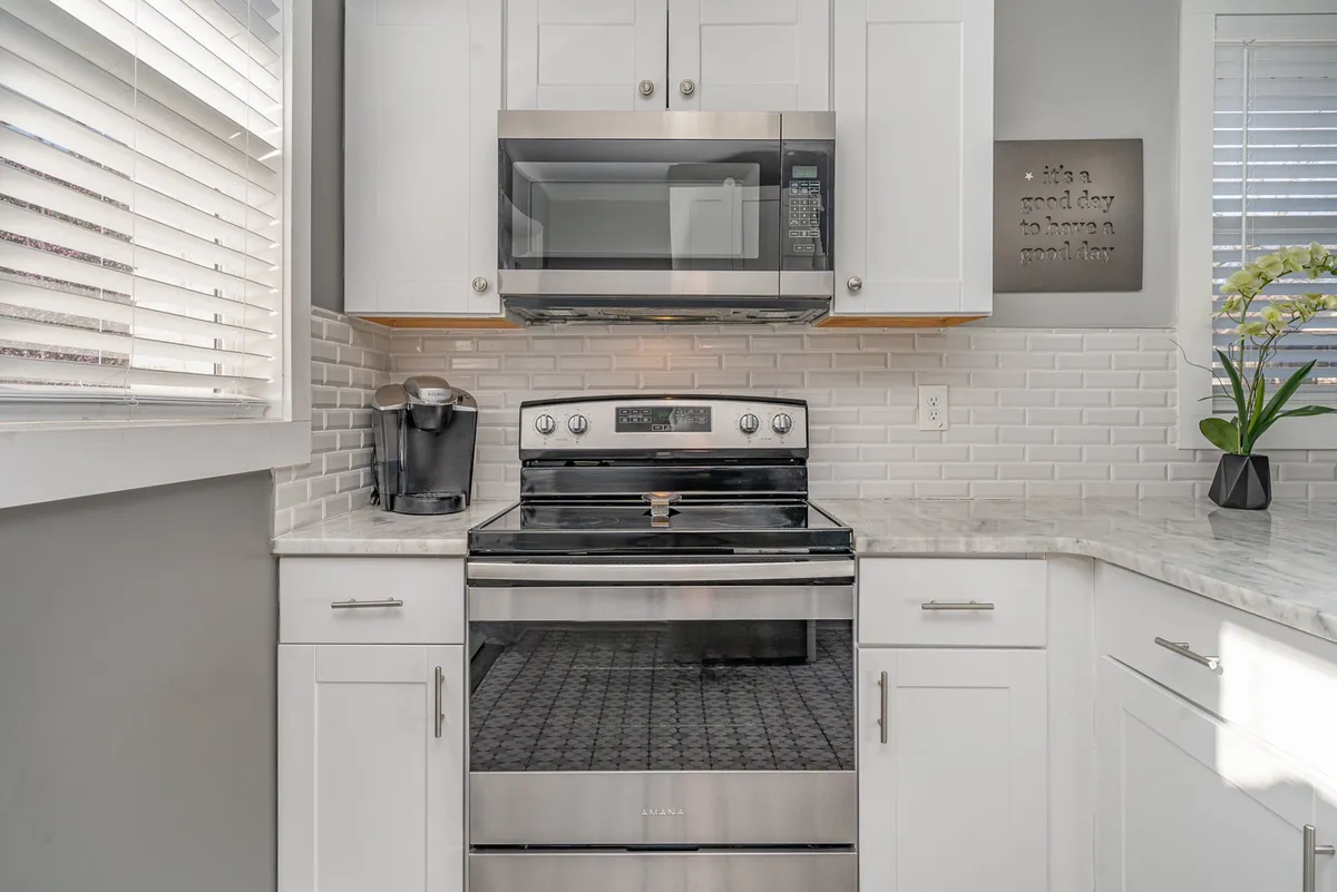 A stylish kitchen with stainless steel appliances, marble countertops, white cabinetry, and decorative touches. The atmosphere is warm and functional, perfect for preparing family meals or hosting small gatherings.